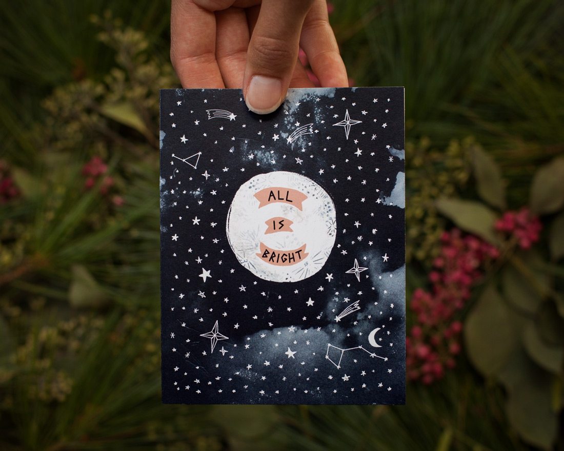 hand holding all is bright with moon holiday card