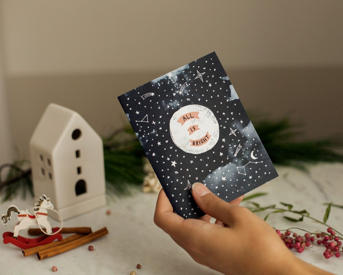 hand holding all is bright moon holiday card