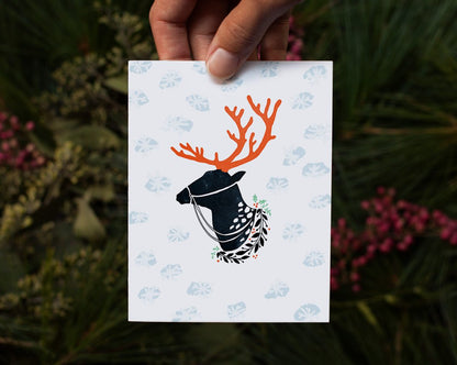 hand holding reindeer christmas card over pine boughs