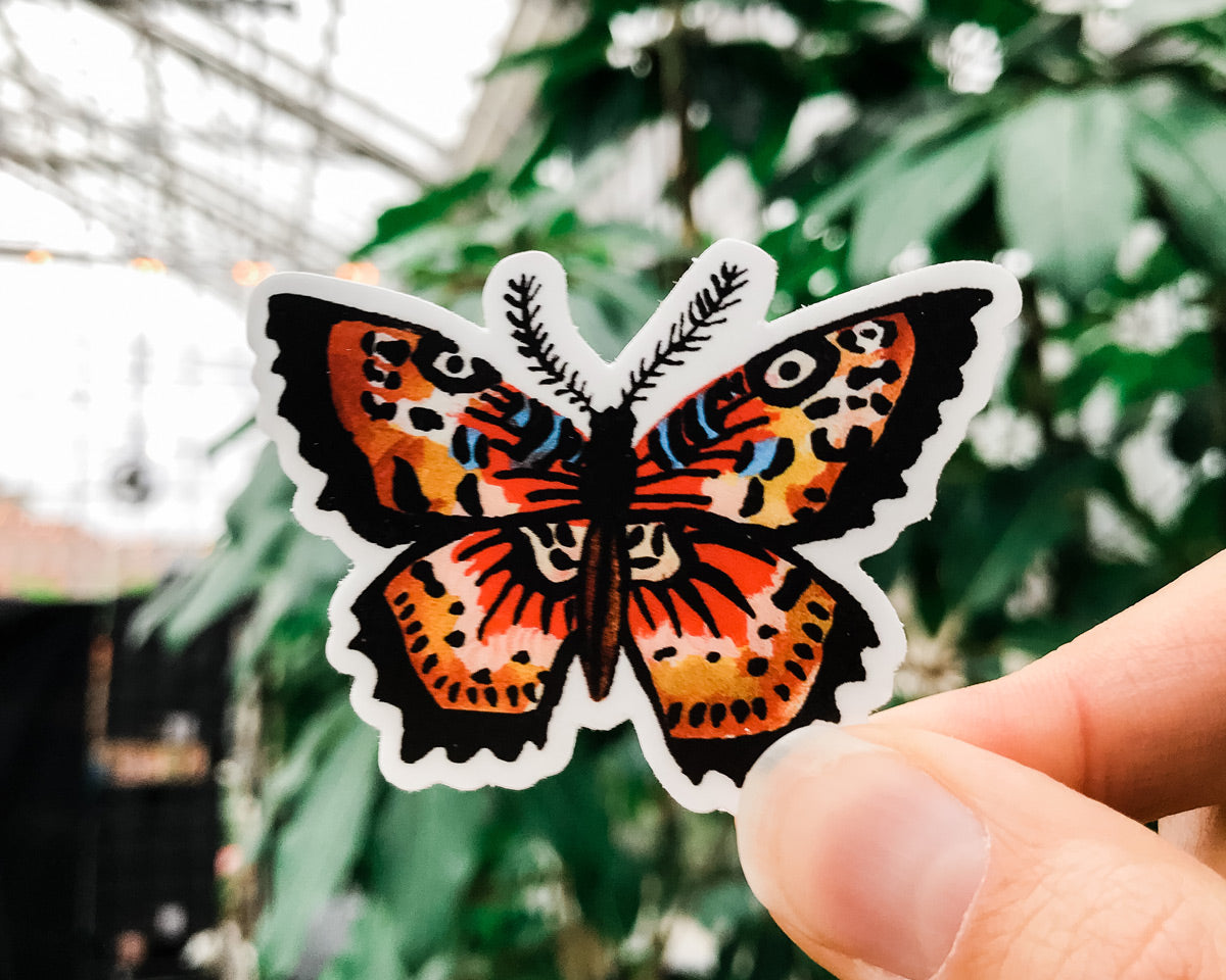 cute butterfly vinyl animal sticker art by wildship studio held against plants