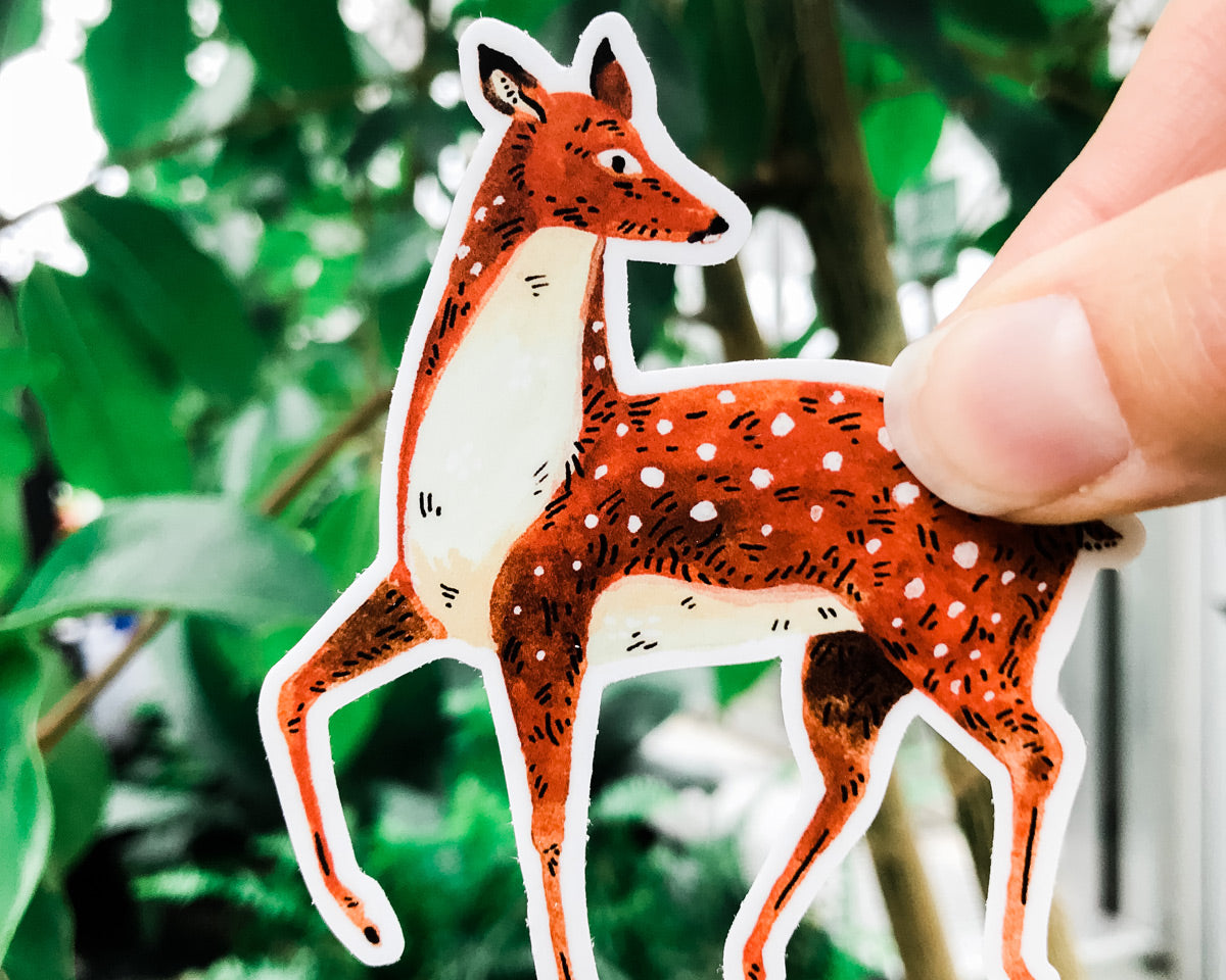 cute deer vinyl animal sticker art by wildship studio held against plants