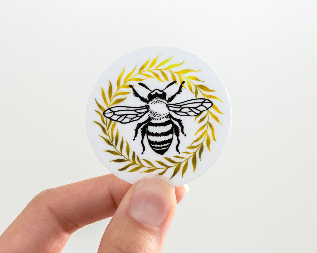 hand holding a cute honey bee and wreath vinyl sticker by wildship studio