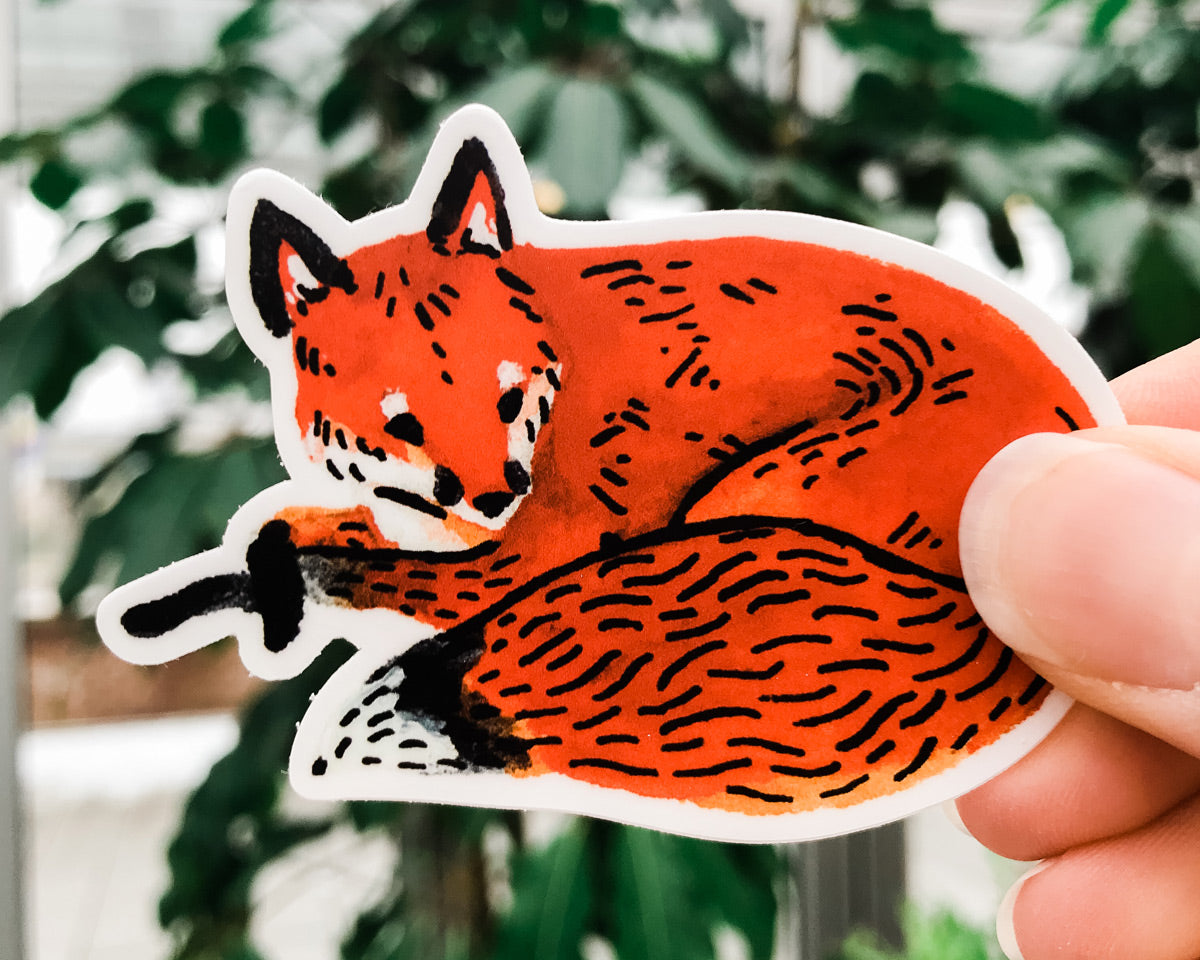 cute red fox vinyl animal sticker art by wildship studio held against plants