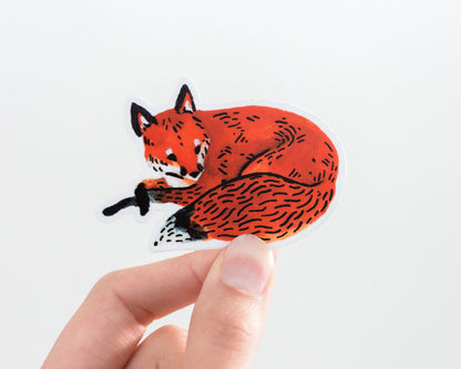 a hand holding a cute red fox vinyl sticker by wildship studio