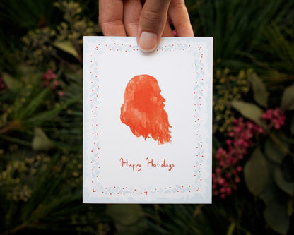 hand holding illustrated Happy Holidays Santa card