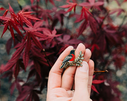 robin enamel pin being held in hand outdoors